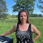 Laura Berg Musamajasta pianon ääressä ulkona. Musiikkipedagogi ja pianonsoiton opettaja.